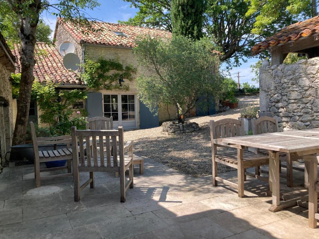 a picnic table and benches in front of a house at Gîte de charme avec grand jardin &amp; piscine in Touffailles