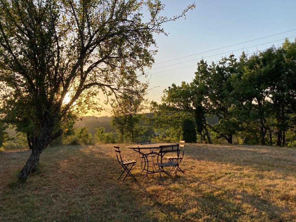 a picnic table and two chairs in a field at Gîte de charme avec grand jardin &amp; piscine in Touffailles