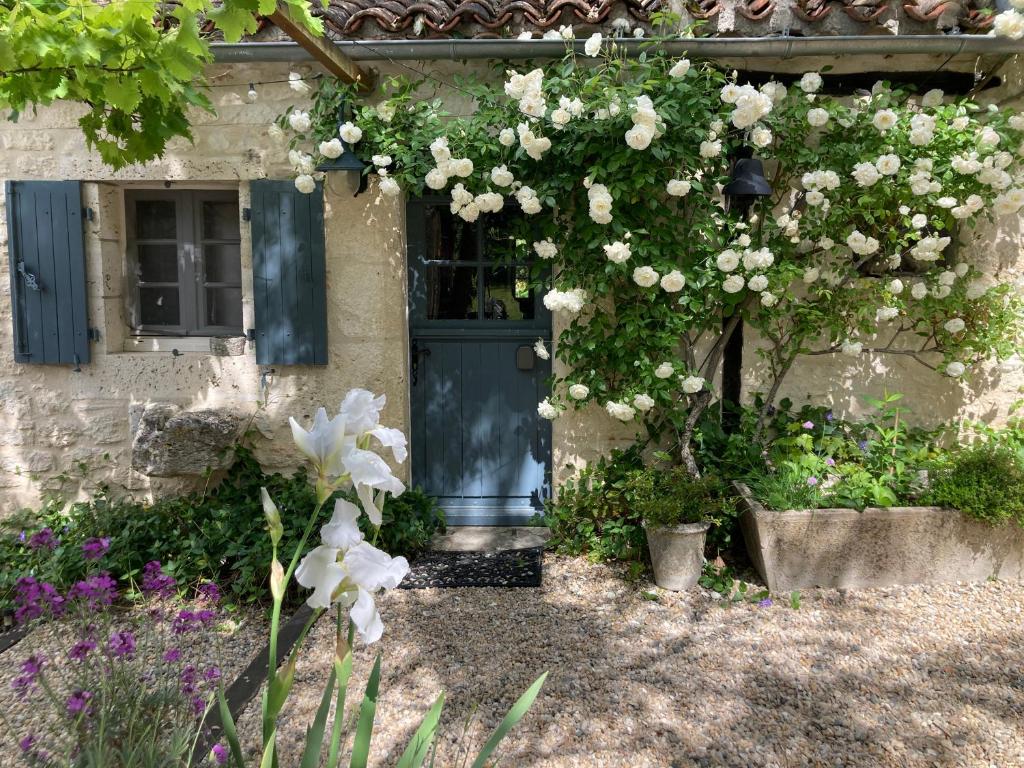 a house with a door and flowers in front of it at Gîte de charme avec grand jardin &amp; piscine in Touffailles