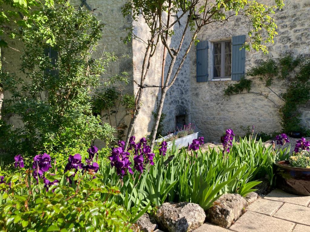 a garden with purple flowers in front of a building at Gîte de charme avec grand jardin &amp; piscine in Touffailles