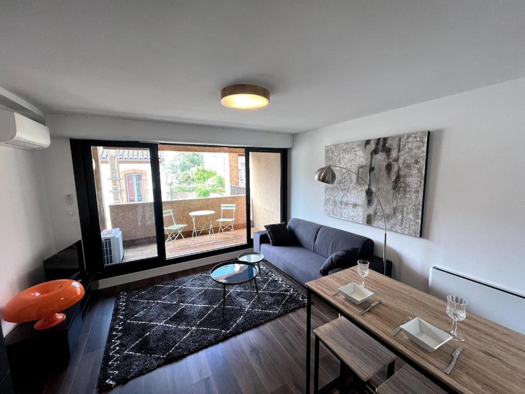ein Wohnzimmer mit einem Sofa und einem Tisch in der Unterkunft Sublime T2 avec balcon in Montauban