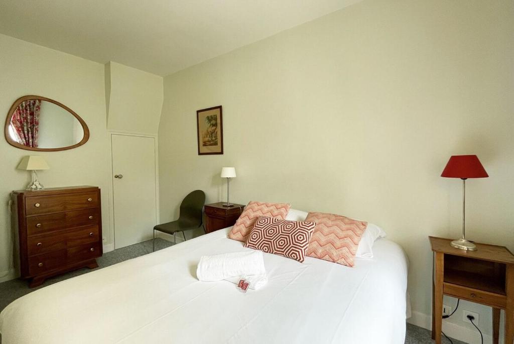 Schlafzimmer mit einem weißen Bett, einer Kommode und einem Spiegel in der Unterkunft Le Cloître pour 4 personnes in Chartres
