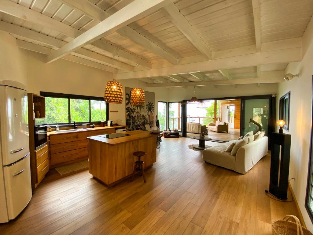 a large kitchen and living room with wooden floors at Lodge Nature in Saint-Leu