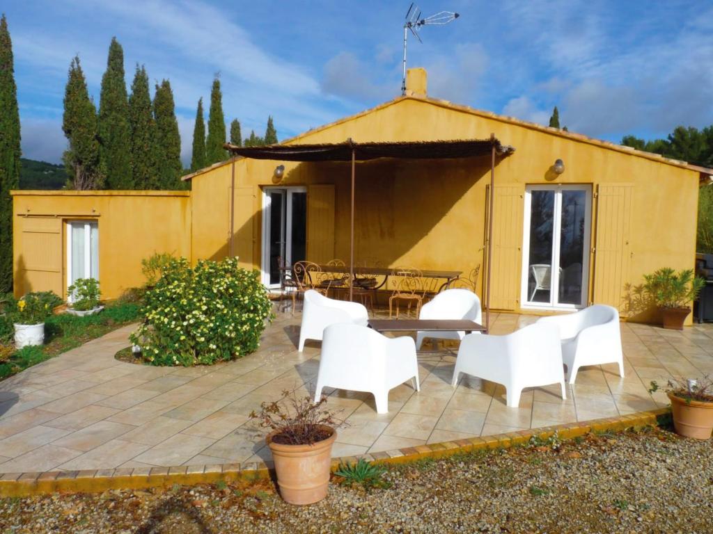 eine Terrasse mit weißen Stühlen, einem Tisch und einem gelben Gebäude in der Unterkunft SALSA in Ceyreste