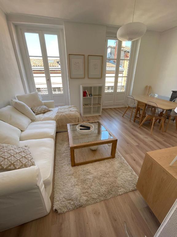 un salon avec un canapé blanc et une table dans l'établissement CAPITOLE - Appartement T2 au cœur de la ville rose, à Toulouse