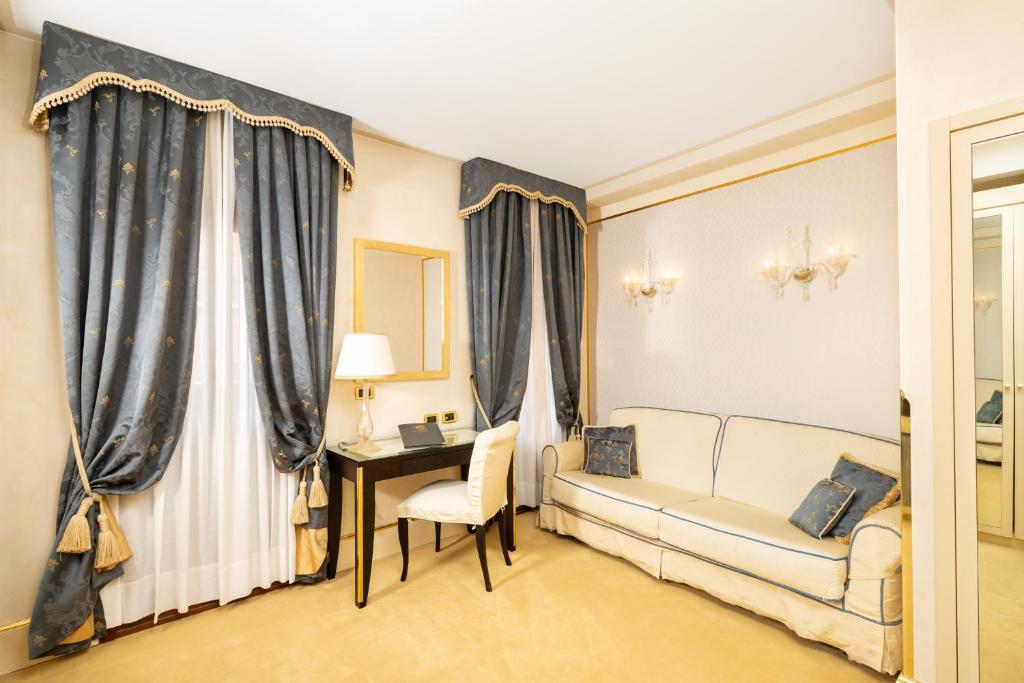 a living room with a couch and a desk and curtains at Hotel A La Commedia in Venice