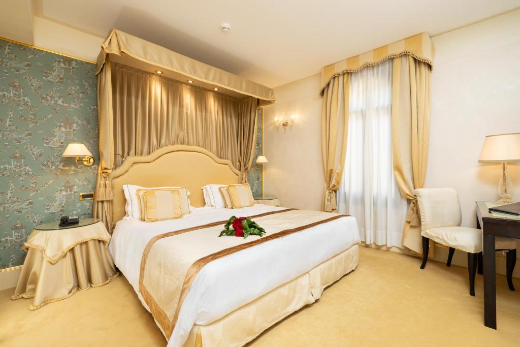 a hotel room with a large bed with flowers on it at Hotel A La Commedia in Venice