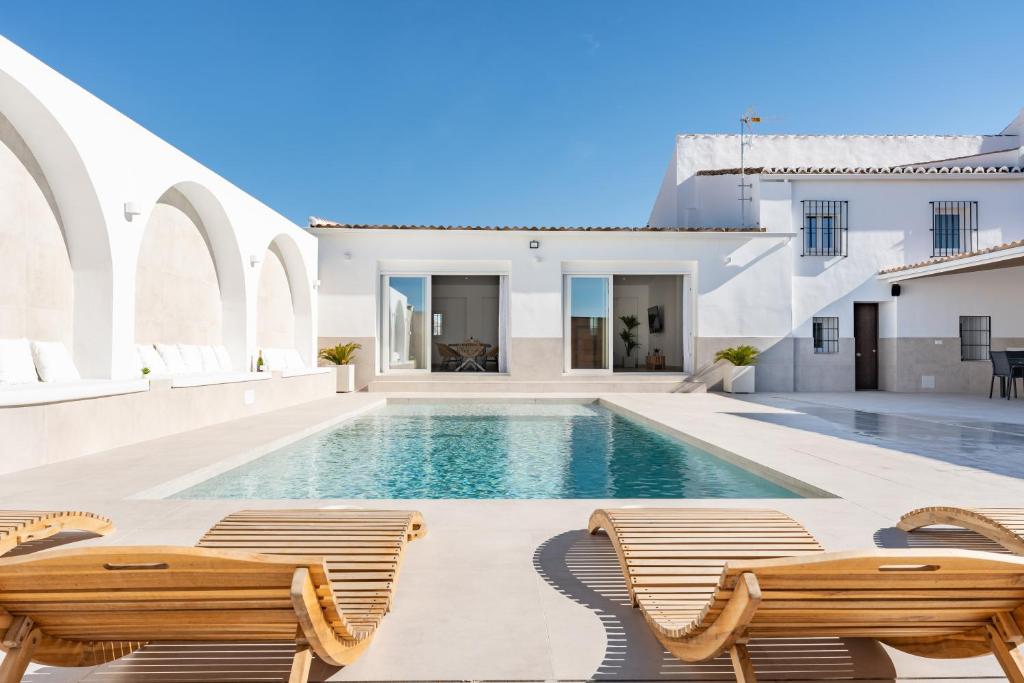 een villa met een zwembad en 2 stoelen bij MalagaSuite Villa Nomada El Torcal in Antequera