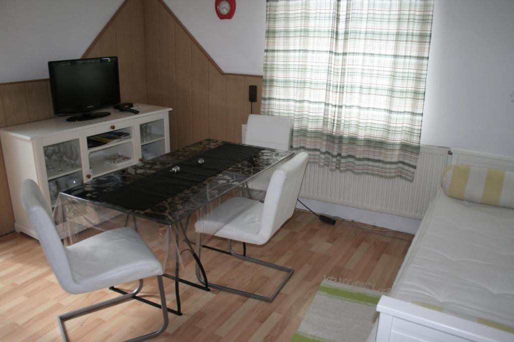 a dining room table with white chairs and a television at Rooming Green Weyregg in Weyregg