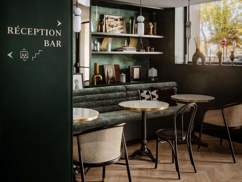 巴黎的住宿－巴黎埃菲爾鐵塔米拉波橋美居酒店，一间带两张桌子的餐厅和一间绿色酒吧