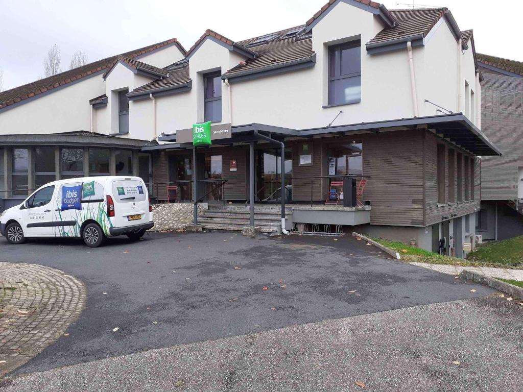 una furgoneta blanca estacionada frente a una casa en ibis Styles Sarrebourg en Sarrebourg