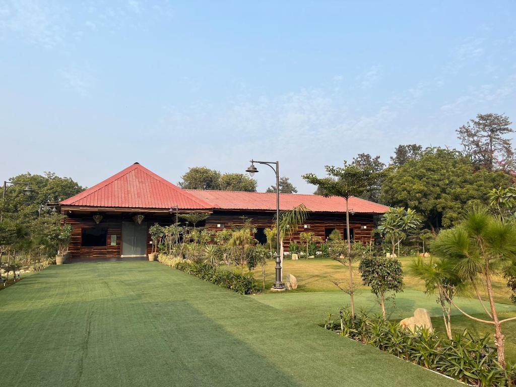 un edificio con techo rojo y patio verde en The Green Wood Palace I Farm House I wedding I Party I 87oo2o5865, en Gurgaon
