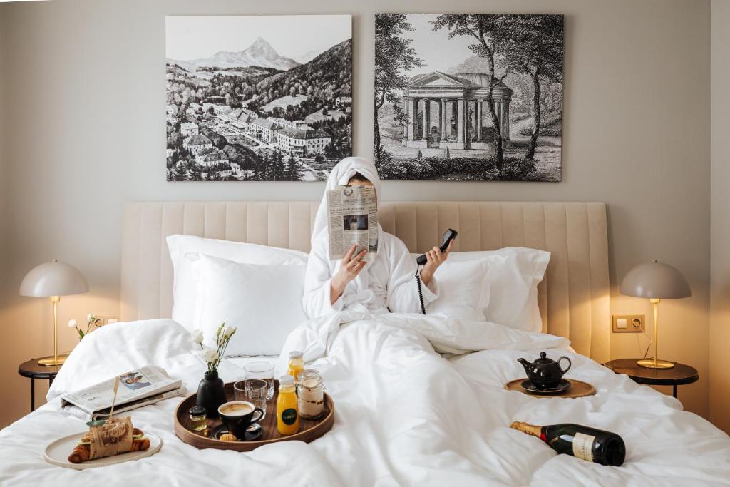 Hotel Slatina في روغاسكا سلاتينا: امرأة مستلقية على السرير تستخدم هواتفها الخلوية