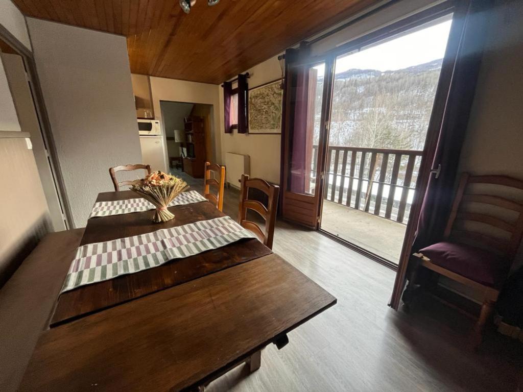 a dining room with a wooden table and a balcony at LES ECRINS in Vallouise