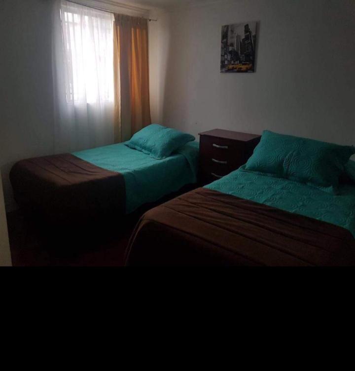 two beds sitting in a room with a window at Hospedaje GYT Caldera in Caldera