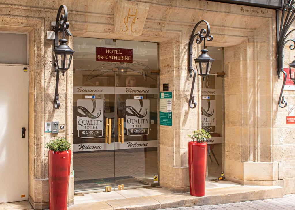 فندق كواليتي سانت كاترين بوردو في بوردو: مبنى به مزهريتين حمرا أمام متجر