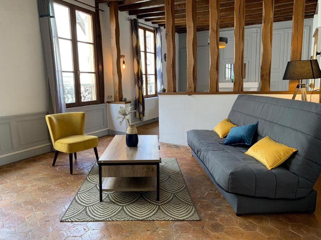 een woonkamer met een bank en een tafel bij Le Clocher- Appartement dans le cœur de ville in Chartres