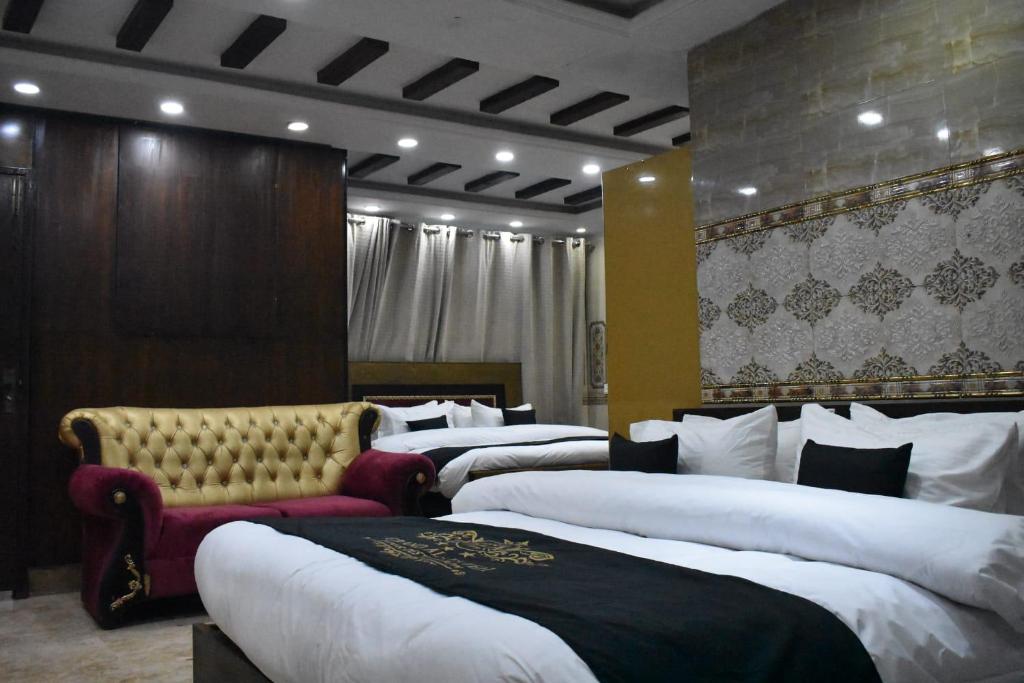 a hotel room with four beds and a couch at Grand AlFateh Hotel in Lahore