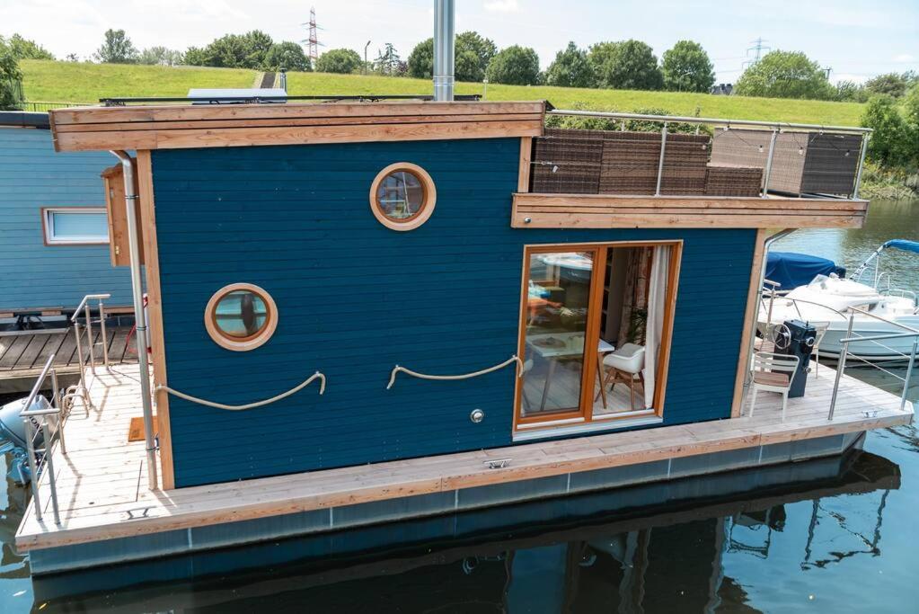 a tiny house on a dock on a body of water at Tiny-Hausboot mit Kamin und Dachterrassenlounge in Hamburg