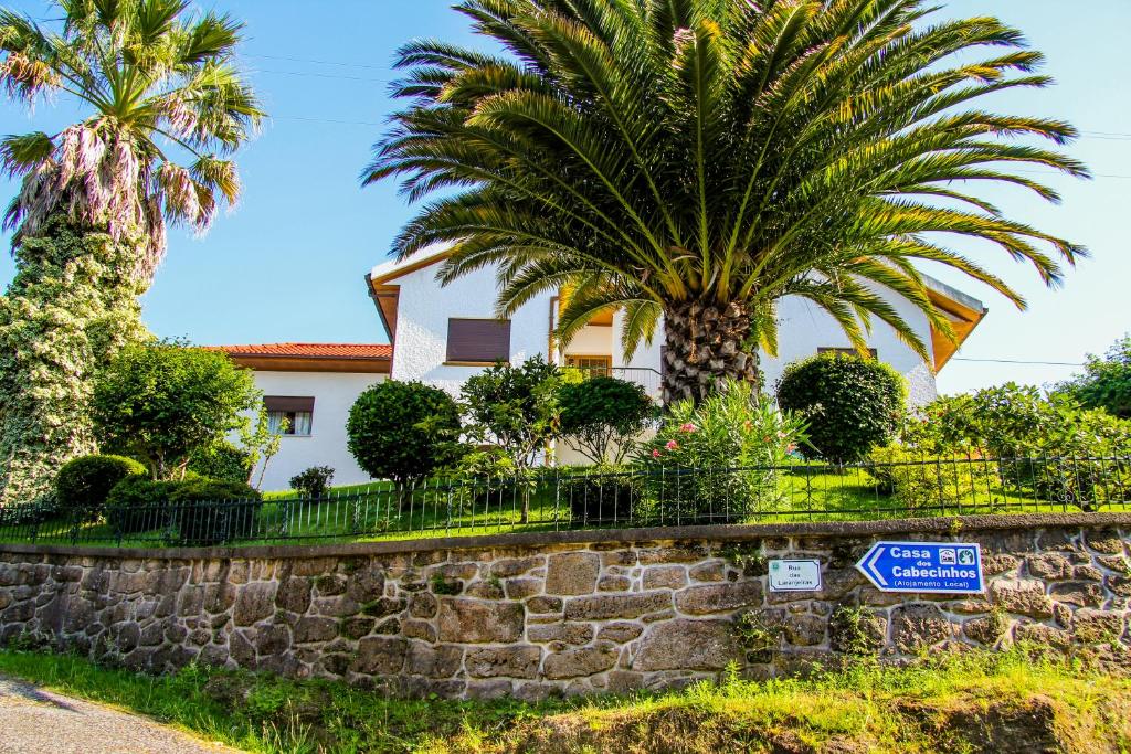 a house with palm trees and a stone wall at Casa Dos Cabecinhos in Paradamonte