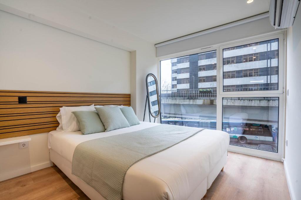 a bedroom with a large bed and a large window at Trindade Bliss: 1BR w/ Free Parking by LovelyStay in Porto