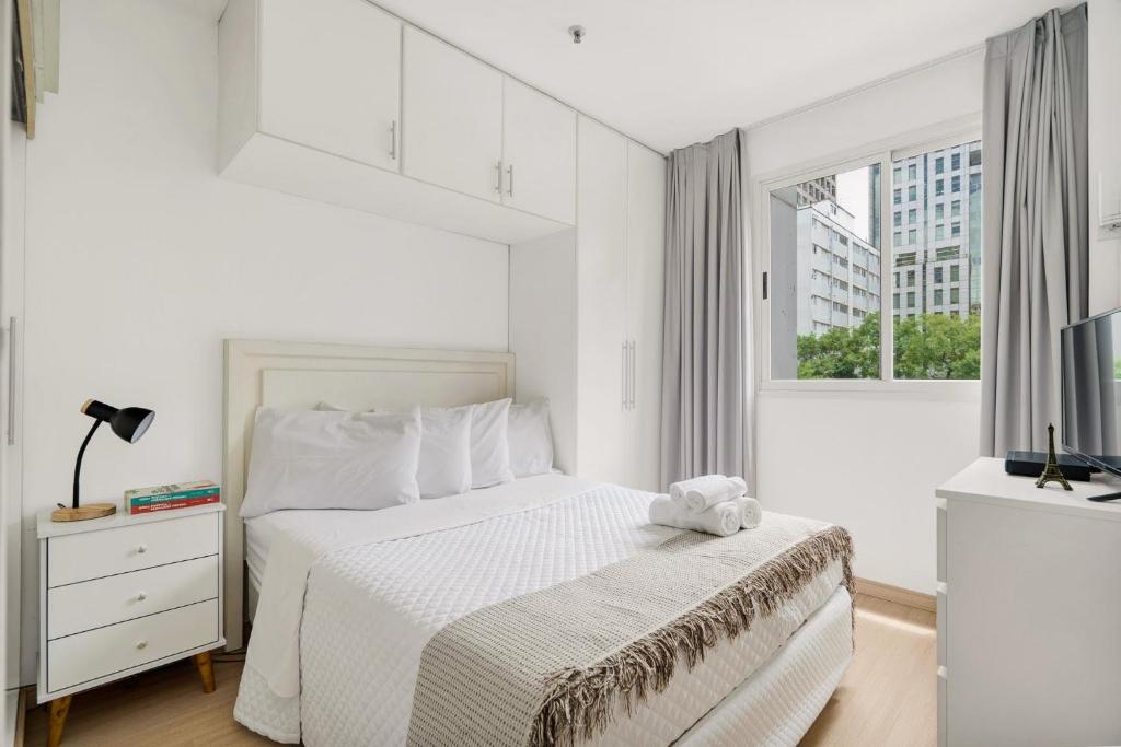 a white bedroom with a bed and a window at Suítes Inside Windham Sao Paulo Paulista in Sao Paulo
