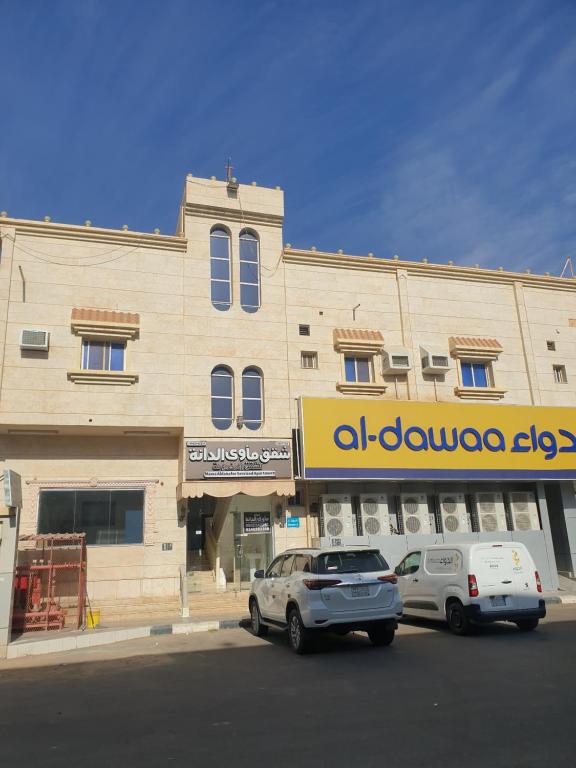 two cars parked in front of a building at شقق مأوى الدانة للشقق المخدومة in Ţubarjal