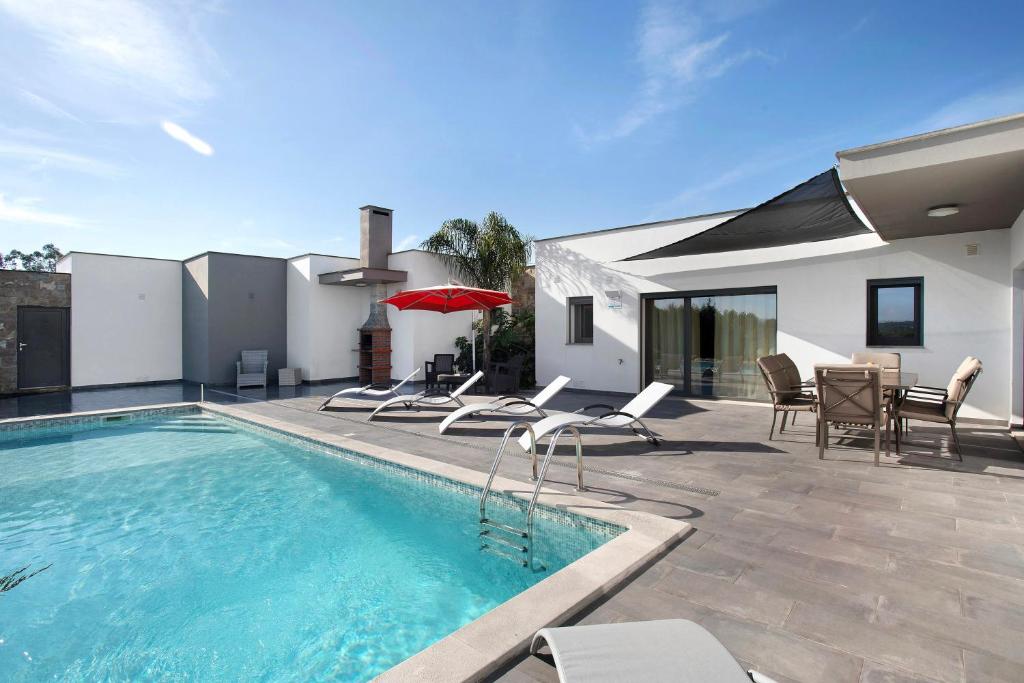 uma piscina com cadeiras e uma mesa e uma casa em Villa Colina em Salir de Matos
