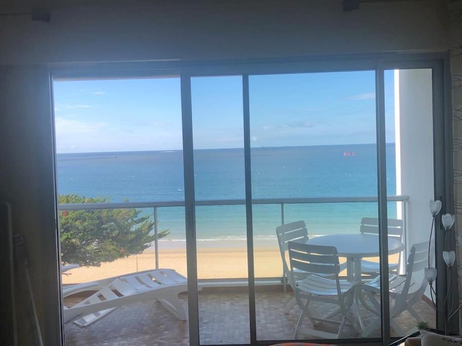 a room with a table and chairs and a view of the beach at Splendide et spacieux appartement, face à la mer in La Baule
