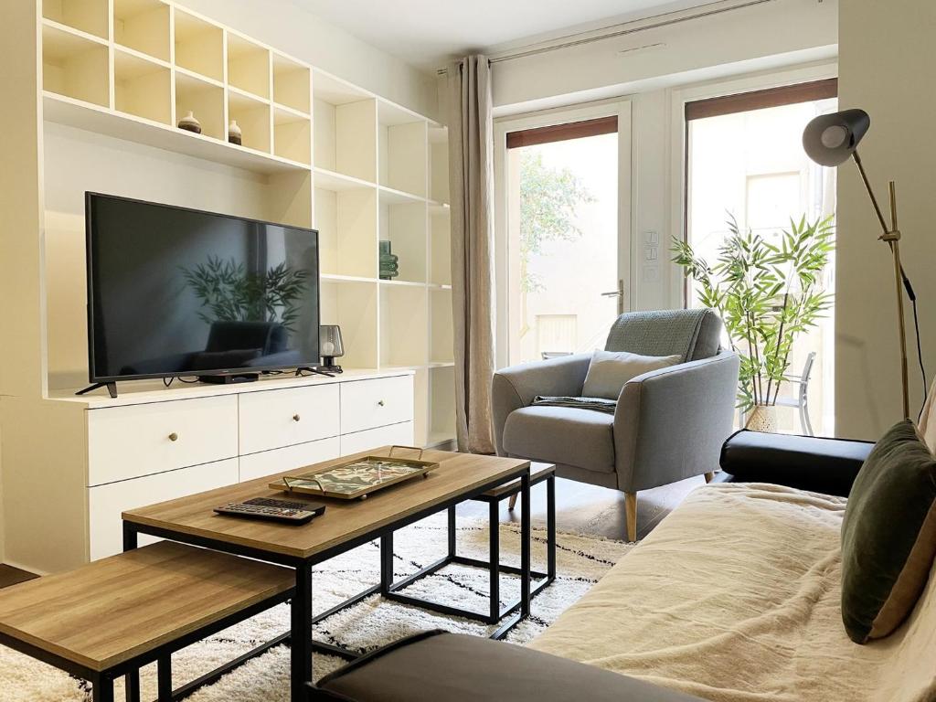ein Wohnzimmer mit einem TV, einem Sofa und einem Tisch in der Unterkunft Le Patio de la Reine Berthe - Parking Included in Chartres