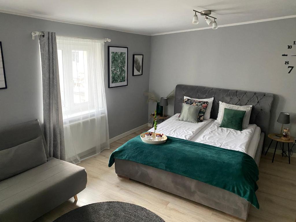 a bedroom with a bed with a green blanket and a couch at Apartament Blue Lagoon in Sopot