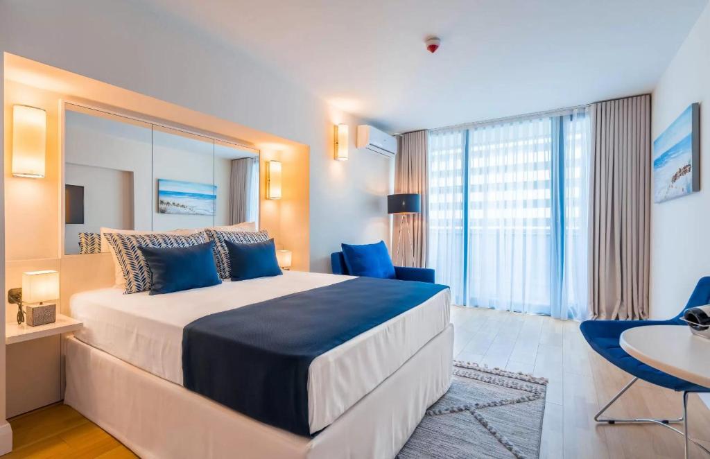 1 dormitorio con 1 cama grande con almohadas azules en Panorama Sea View Central City Batumi & ApartHOTEL en Batumi