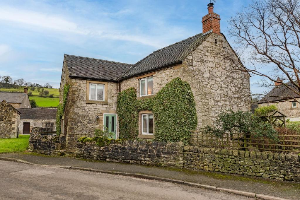 a stone house with ivy on the side of it at 1 The Barn - Brassington in Brassington