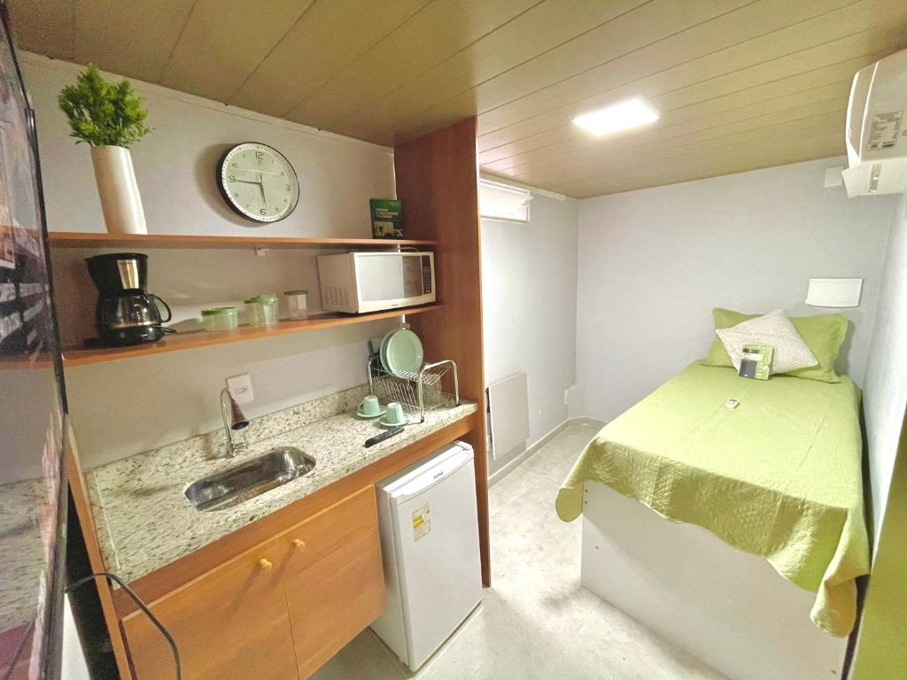 um pequeno quarto com uma cama e um lavatório em SUÍTE independente com Ar, Wifi, Smartv e Cozinha em Macaé