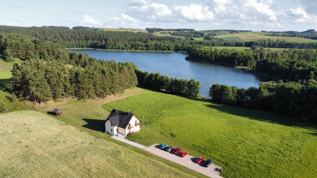 z góry widok na dom na polu obok jeziora w obiekcie Apartamenty Nad Jeziorem w mieście Postawele