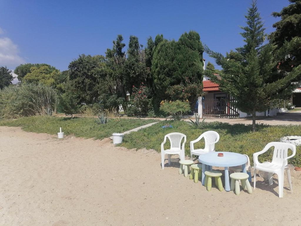 a group of white chairs and a table in the sand at Porto Almira Studio in Nikiti