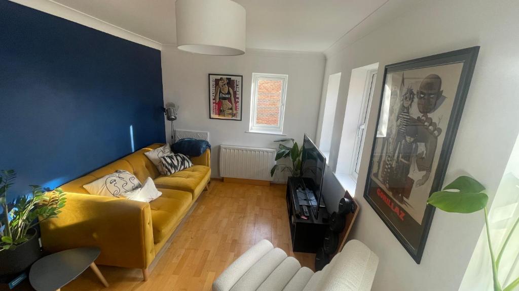een woonkamer met een gele bank en blauwe muren bij Best Spot near Stratford in Londen