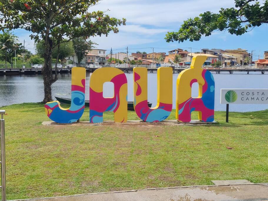 a sign that is painted on the grass near a river at Praia de Jaúa, Piscina privativa, churrasqueira. in Camaçari