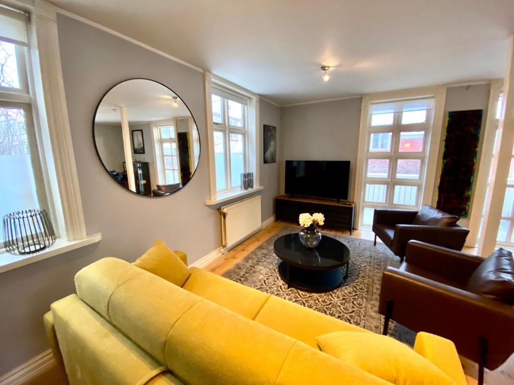 a living room with a yellow couch and a mirror at Day Dream - Vesturgata 5a Luxury Apartment in Reykjavík