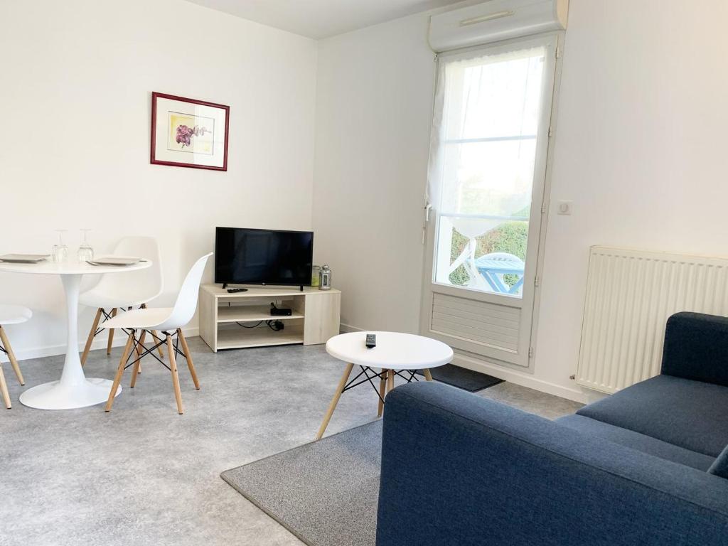 un salon avec un canapé bleu et une table dans l'établissement Le Matisse, à Mainvilliers