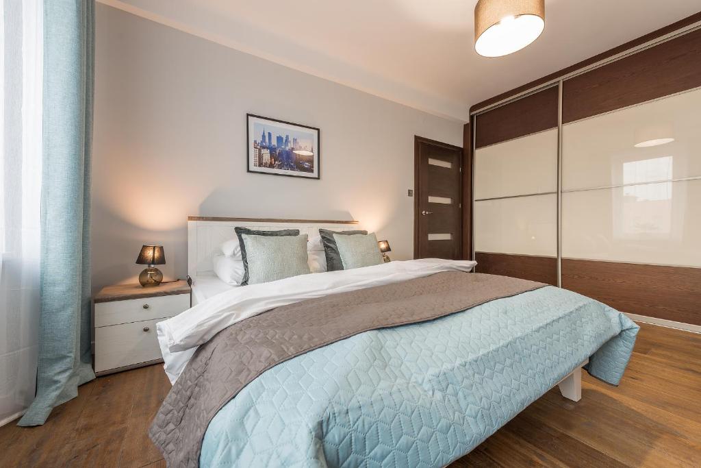 a bedroom with a large bed with a blue blanket at Chmielna Apartments Warsaw Center in Warsaw