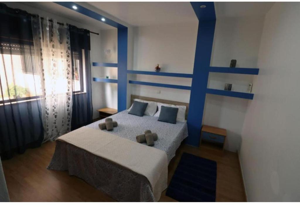 a bedroom with a blue bed with two teddy bears on it at Apartamento Carmix in Portimão