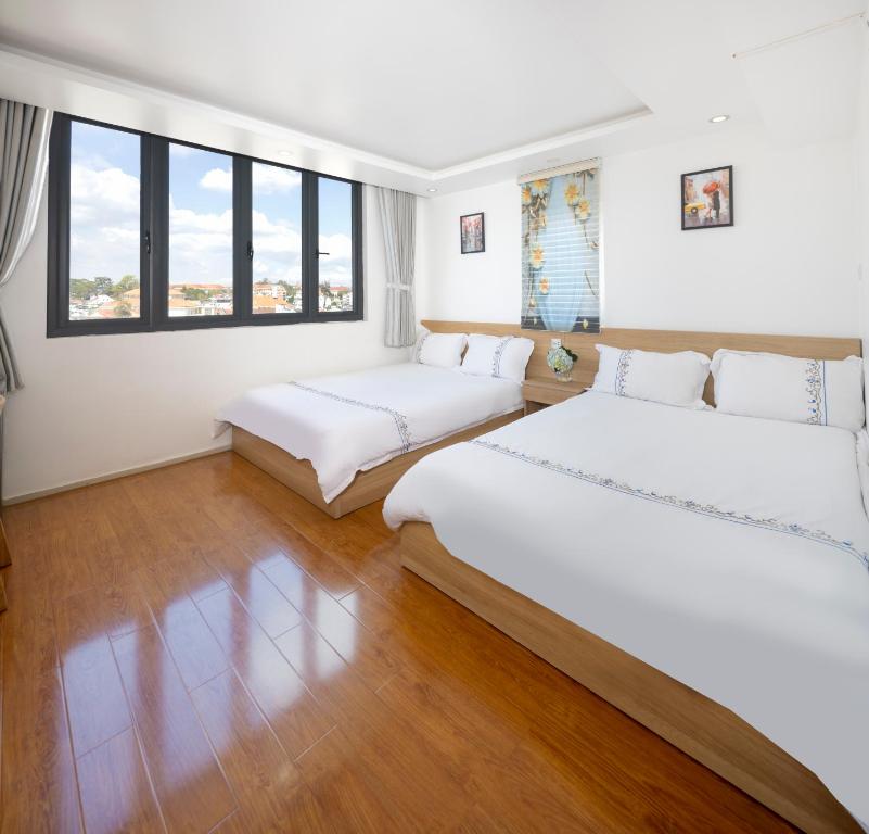 2 Betten in einem Zimmer mit Holzböden und Fenstern in der Unterkunft Hotel Pansy in Da Lat