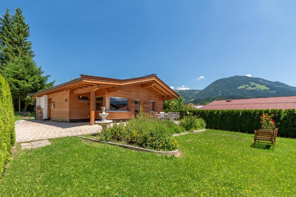 a wooden cabin with a yard with green grass at Ferienhaus 12 im Feriendorf Kirchdorf in Kirchdorf in Tirol