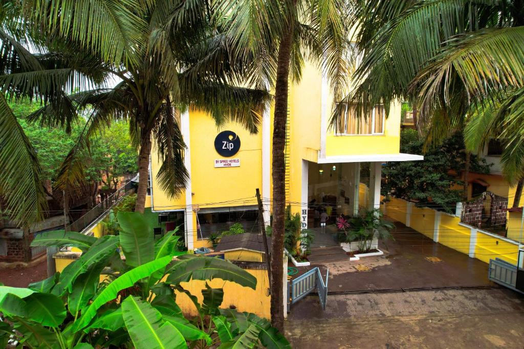 a yellow building with palm trees in front of it at Zip By Spree Hotels Hyde Goa in Goa Velha