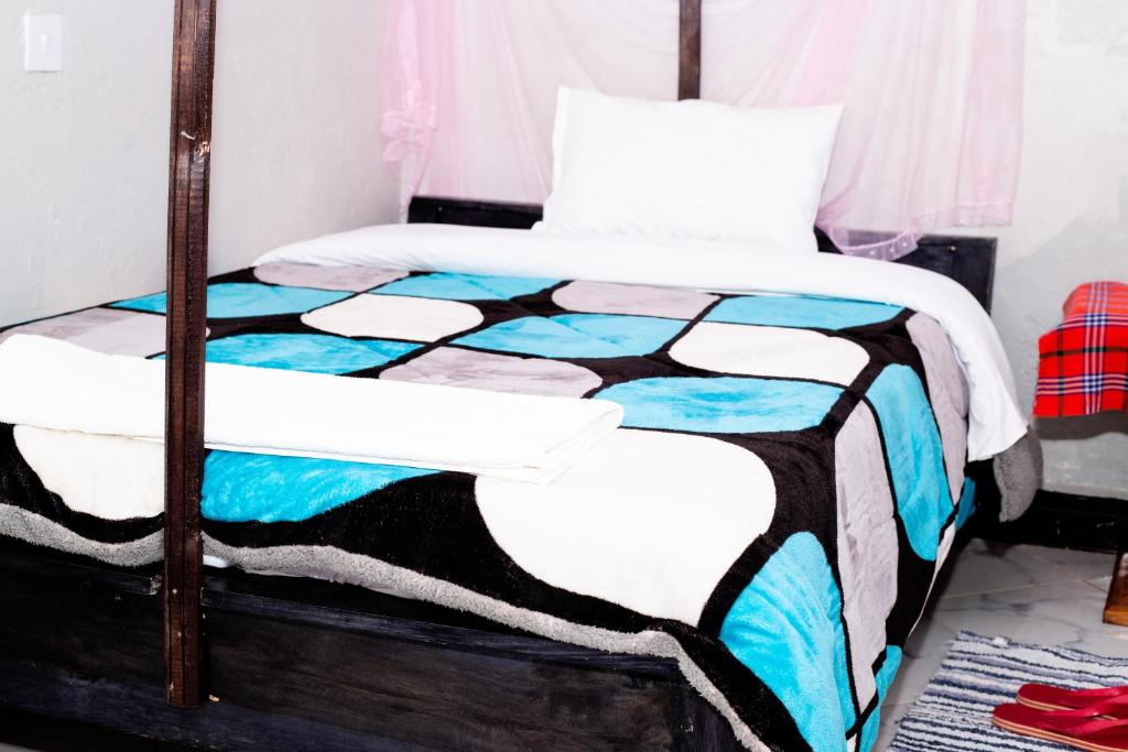 VINTEX GUEST HOUSE في Kimana: غرفة نوم مع سرير ولحاف ملون