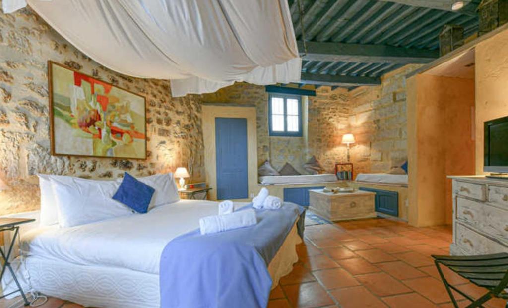 une chambre avec un lit et une télévision dans une pièce dans l'établissement Les suites de charme du Portalet, à Uzès