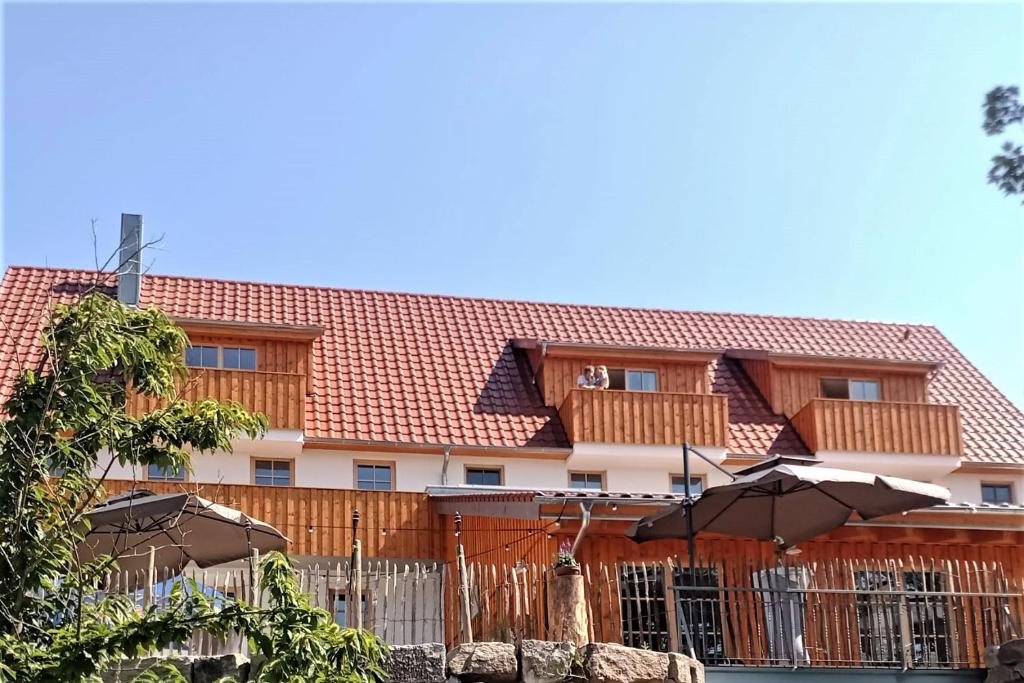 a building with a fence and umbrellas in front of it at Lana Salta Alpakas - Gemütliche Gästezimmer auf dem Bauernhof in Murrhardt