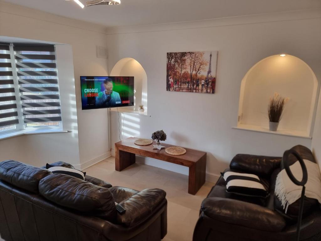 ein Wohnzimmer mit 2 Ledersofas und einem TV in der Unterkunft Dulverton house - 3 bed house /sleeps 6+ driveway+close to M1 in Nottingham