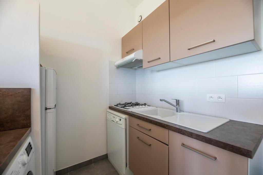 a small kitchen with a sink and a refrigerator at Résidence Santa Monica in Bonifacio